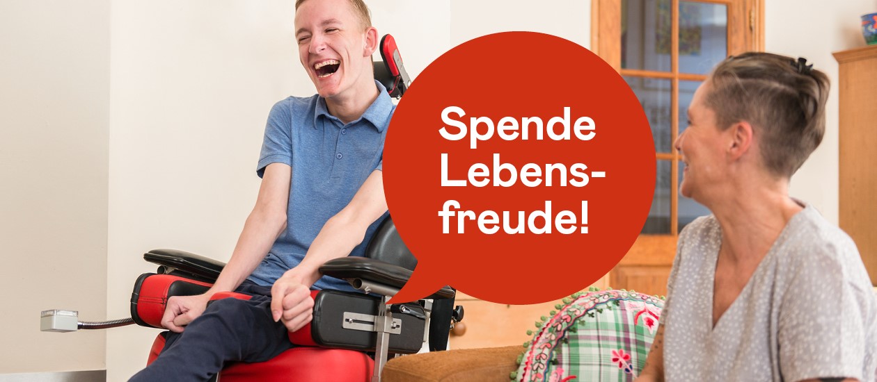 Spende Lebensfreude. junger Mann im Rollstuhl der herzlich mit seiner Betreuerin lacht 